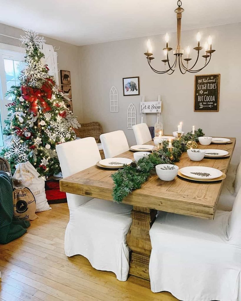 Christmas dining table with a natural evergreen runner, linen napkins, ceramic plates, and warm wood