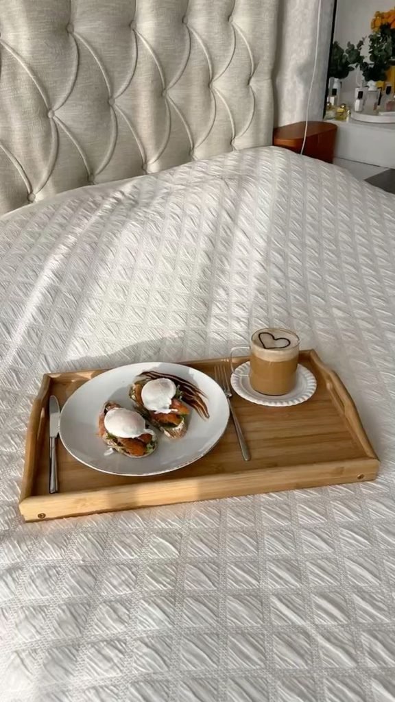 Wooden decorative tray styled on a cozy bed with a book and ceramic vase