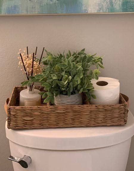Small decorative tray styled on top of a toilet tank with ceramic accessories