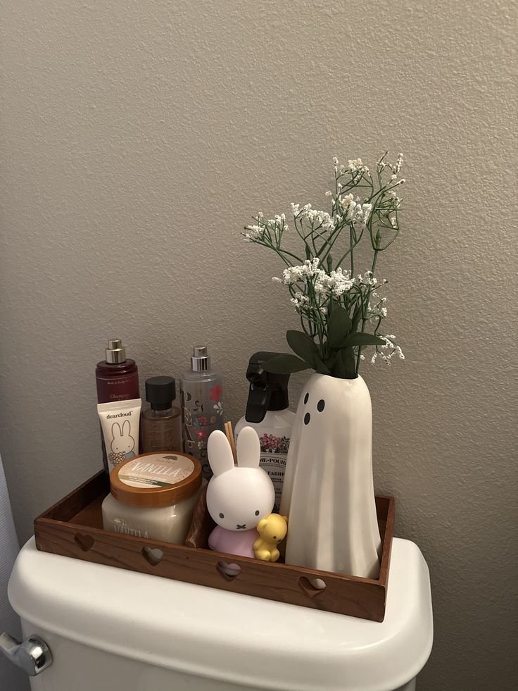 Layered toilet tank decor with a vase plant tray and ceramic objects