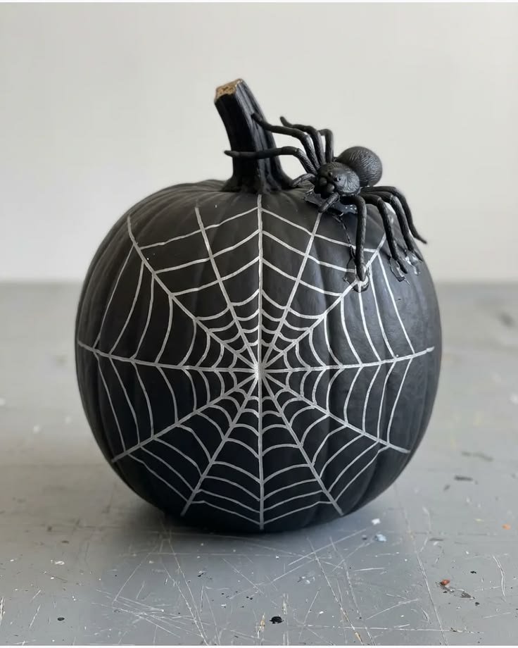 Black pumpkin painted with a white spiderweb