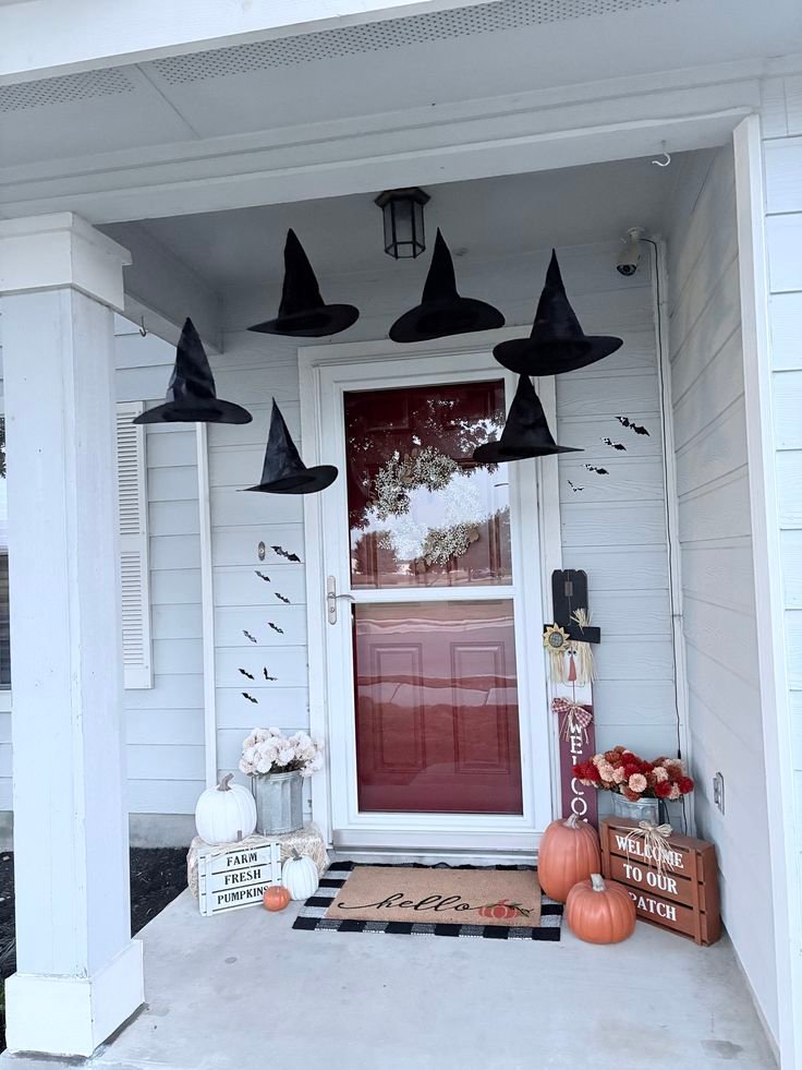 Oversized black witch hat with a purple bow hanging on an olive green front door.