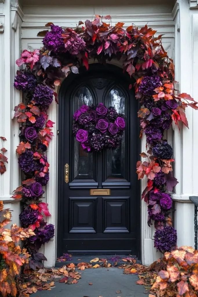 Black front door framed by a gothic burgundy Halloween garland with dark roses.
