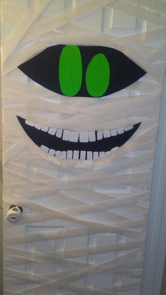 Front door wrapped in white fabric like a giant Halloween mummy with large eyes.