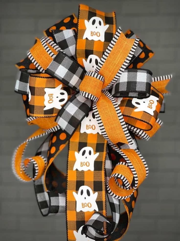 Oversized striped Halloween bow with three hanging white ghosts on a dark door.