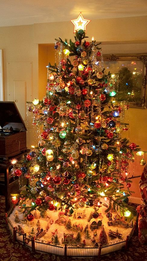 Vintage Christmas tree with colorful glass ornaments, silver tinsel and nostalgic lights.