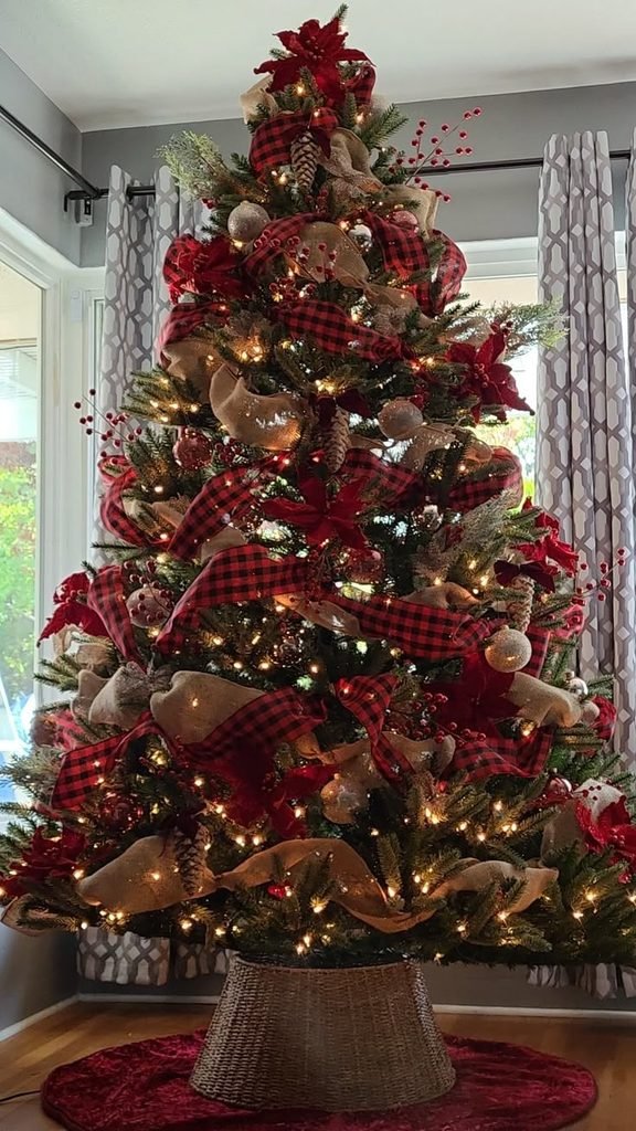 Cozy Christmas tree decorated with tartan plaid ribbons, red ornaments and wooden bells.