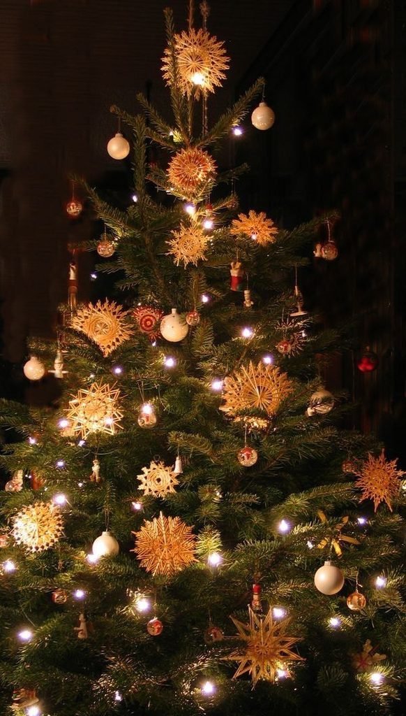 Scandinavian Christmas tree decorated with straw stars, wooden ornaments and linen ribbons.
