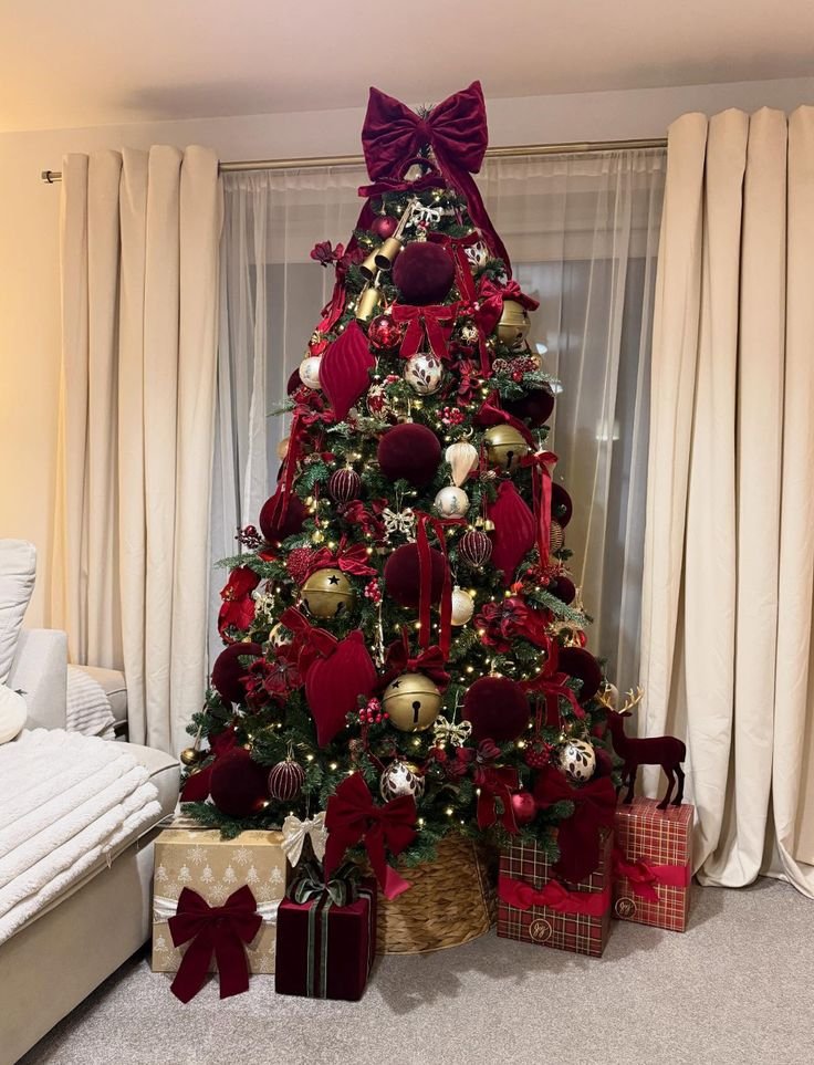 Elegant burgundy Christmas tree with oversized velvet bows and antique brass ornaments.