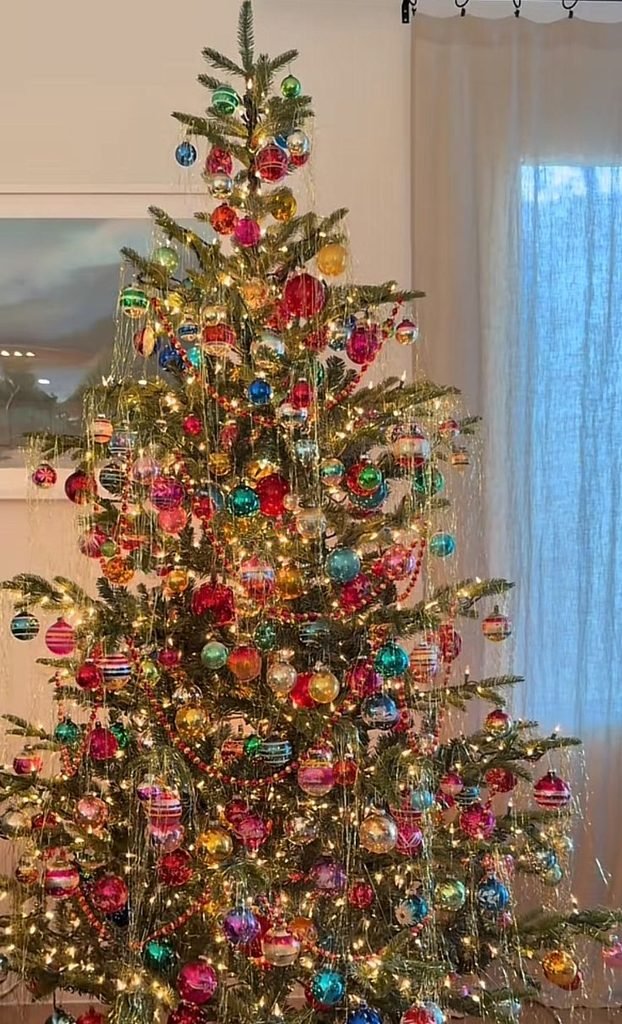 Retro Christmas tree with colorful vintage glass ornaments, tinsel and multicolored lights.