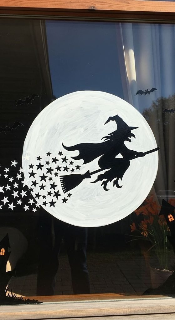 Witch flying across the moon painted on a Halloween window