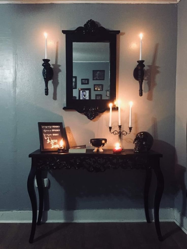 Gothic Halloween hallway console with black candelabras, antique books and a brass clock.
