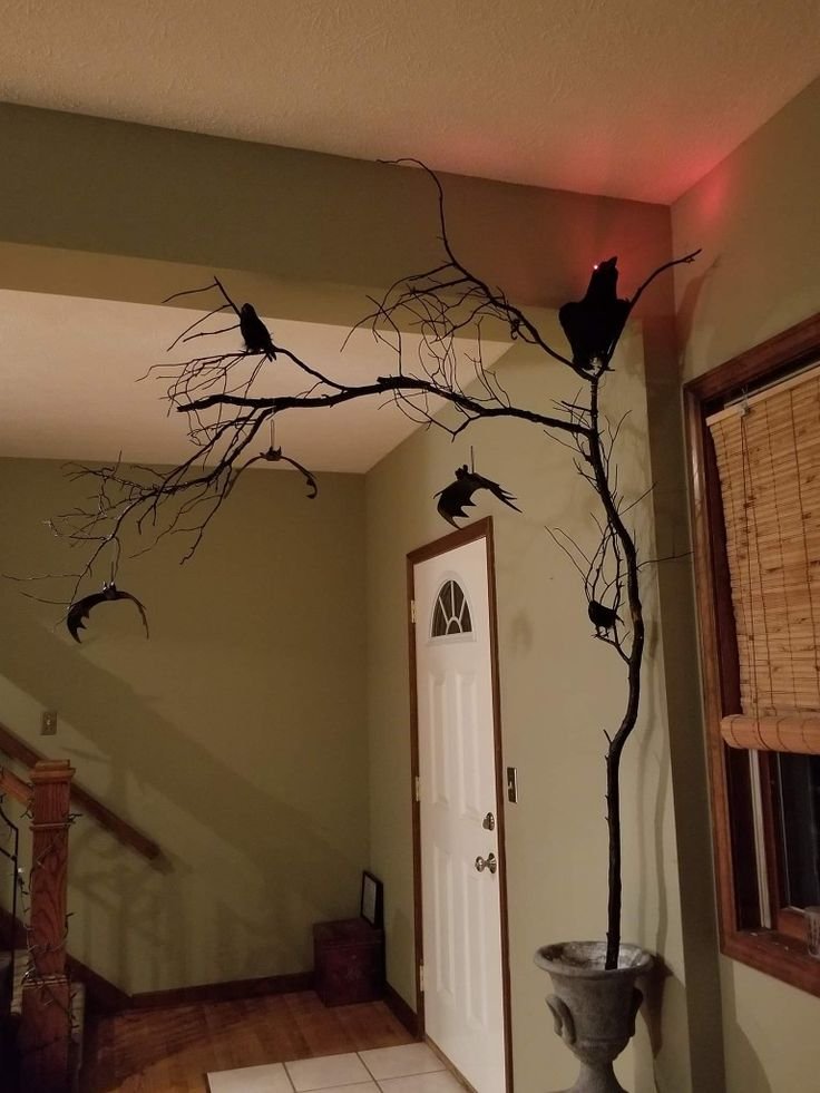 Twisted branches with hanging black bats arranged on a Halloween hallway console.