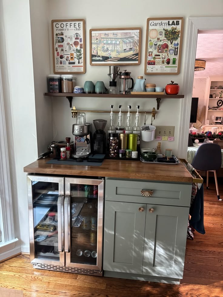 Home coffee bar with a compact mini fridge, espresso machine, ceramic mugs, glass jars, and coffee accessories