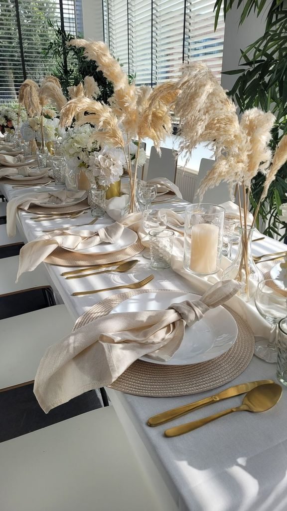 Elegant cream and gold Thanksgiving tablescape with ivory dinnerware, gold accents, and greenery.