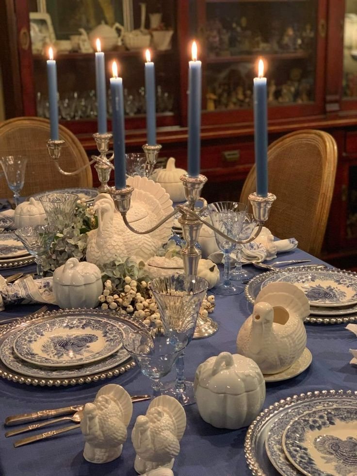 Cozy Thanksgiving table illuminated by warm candlelight with neutral linens, ceramics, and greenery.