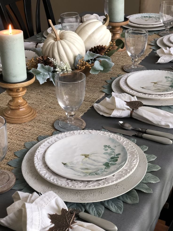 Simple Thanksgiving table with white stoneware, linen napkins, wooden serving boards, and branches.
