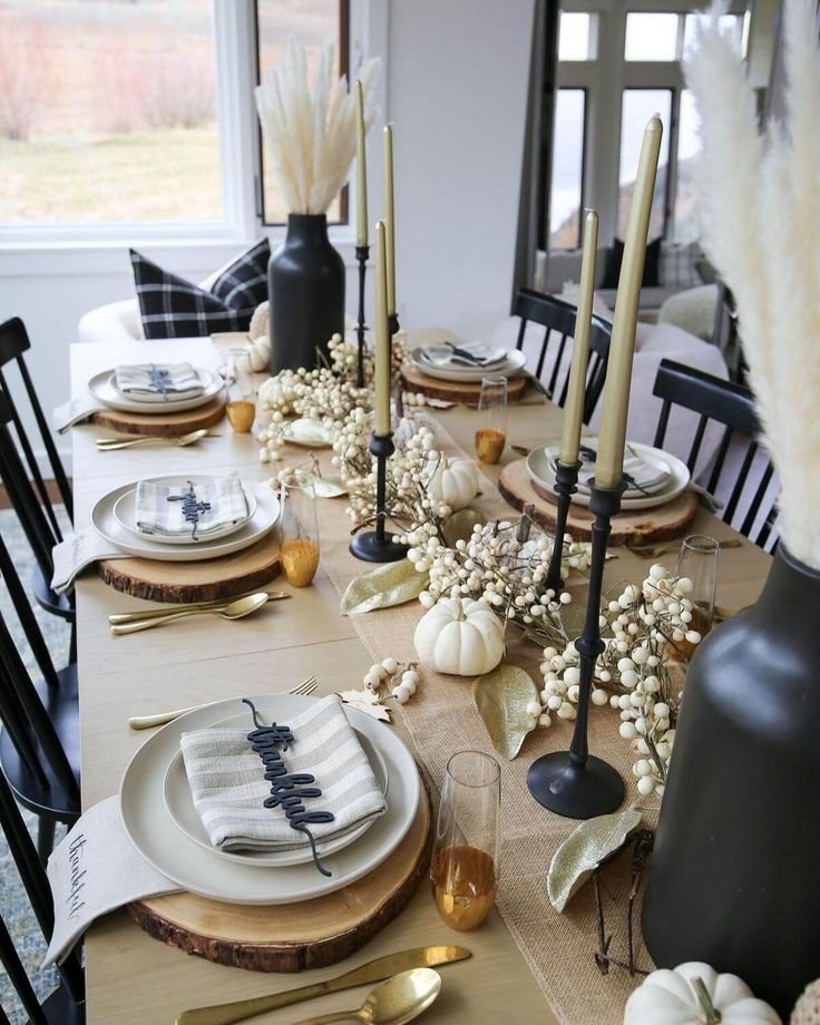 Modern Thanksgiving table with black accents, cream linens, natural wood, and greenery.