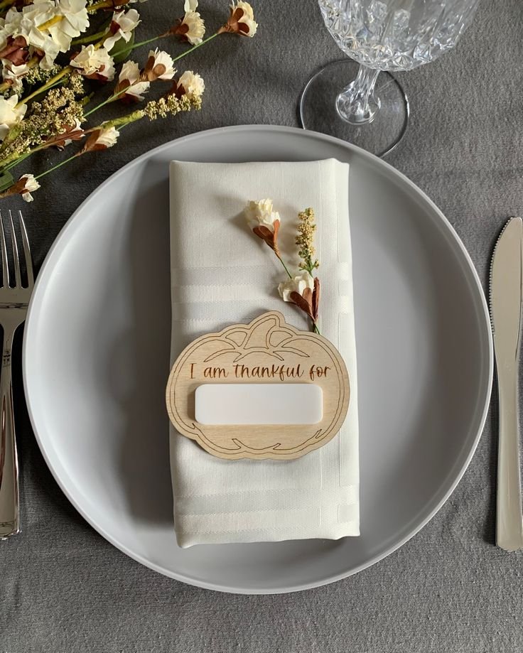 Personalized Thanksgiving place setting with a linen napkin, name card, ceramic plate, and botanical accent.
