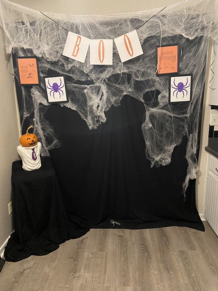Halloween party photo corner with a black backdrop, paper bats, vintage frames, and costume props.