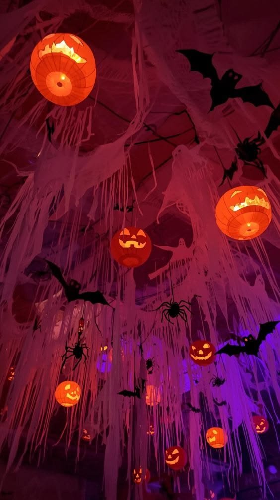 Halloween party wall with black paper bats, a vintage mirror, and a large spiderweb decoration.