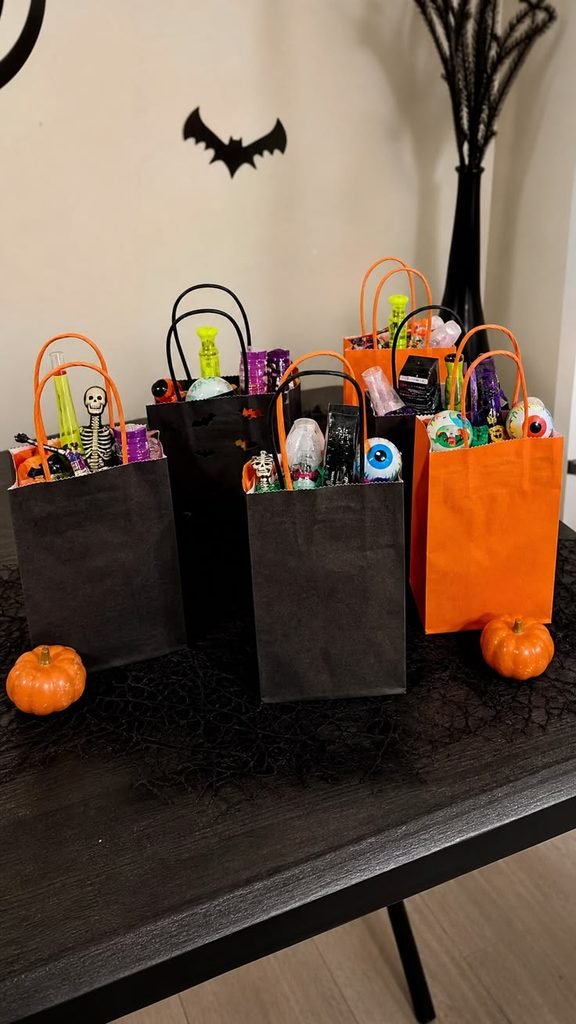 Halloween house party ideas favors in black bags and kraft boxes with seasonal ribbons and wrapped treats.