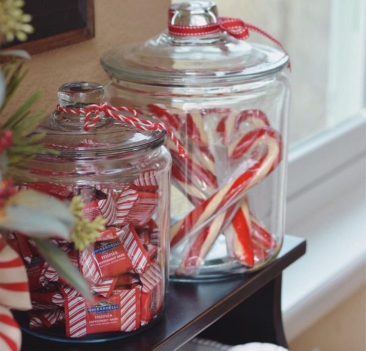 Red and white Christmas mason jar centerpiece with candy canes, berries, and greenery.