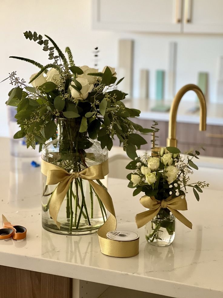 Elegant Christmas mason jar centerpiece with evergreen greenery, gold ribbon, and gold ornaments.