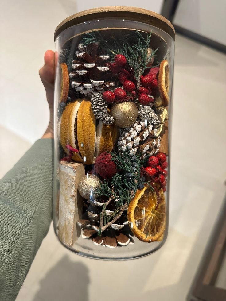 Christmas mason jar centerpiece with dried orange slices, evergreen branches, cinnamon, and pinecones.
