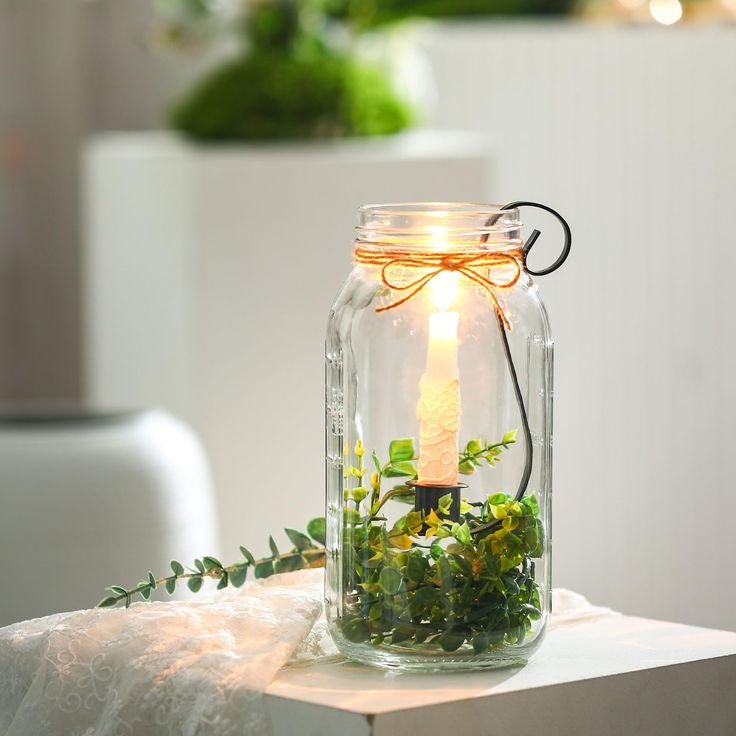 Mason jar Christmas lantern centerpiece with warm white fairy lights, greenery, and pinecones.