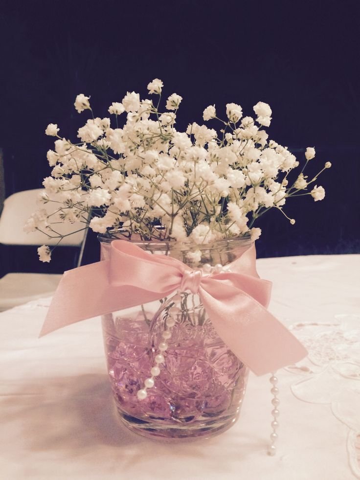 Pearl and satin bow Christmas mason jar centerpiece with frosted branches and white flowers.