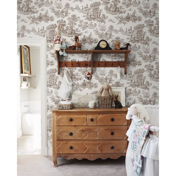 Blue and white toile wallpaper behind a classic bookshelf with books and ceramic decor
