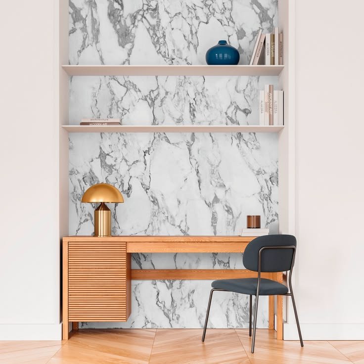 White marble-effect wallpaper behind modern shelves with black, brass, and ceramic decor