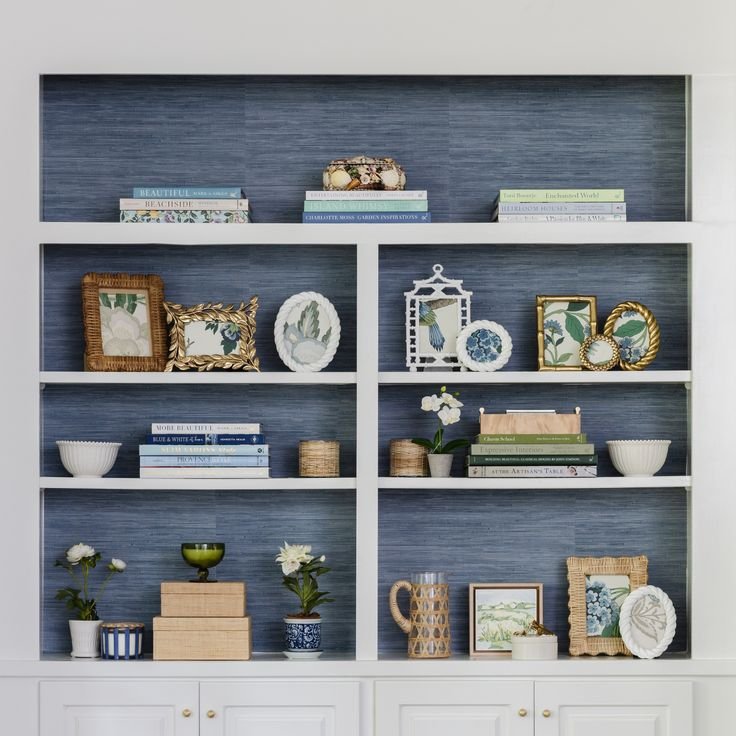Grasscloth-look wallpaper behind wood shelves with woven baskets, ceramics, and books