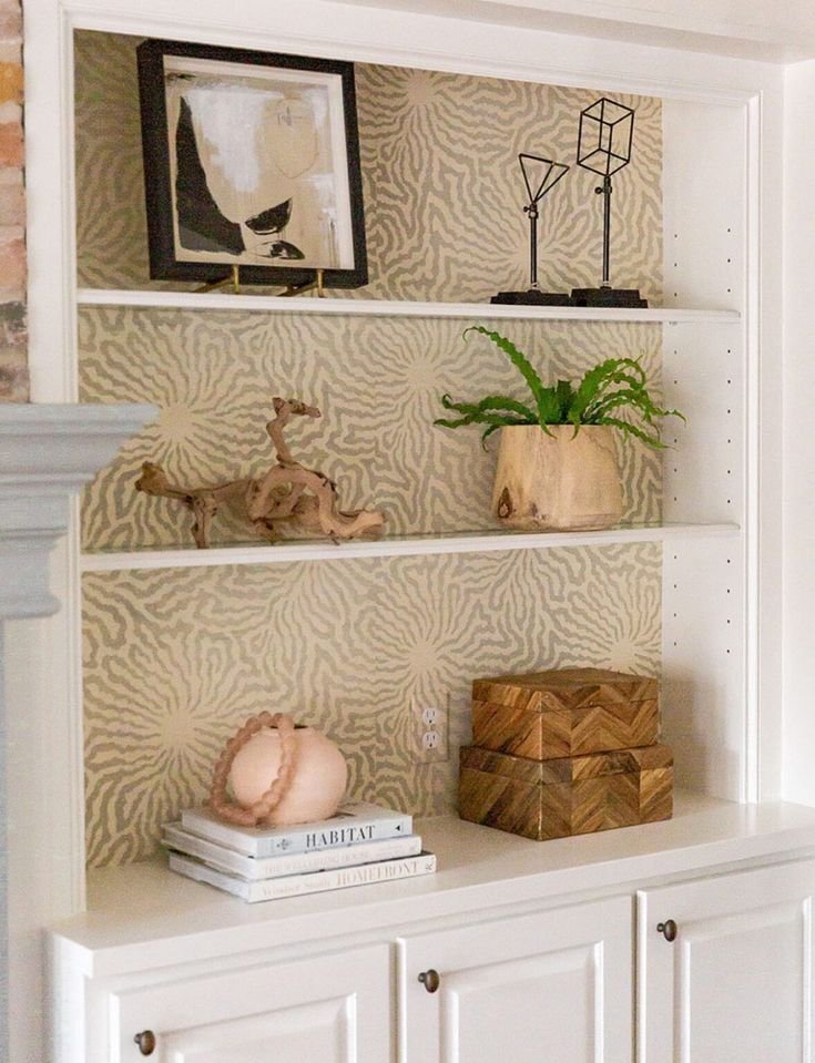 Abstract wallpaper in muted colors behind modern shelves with sculptural ceramic decor