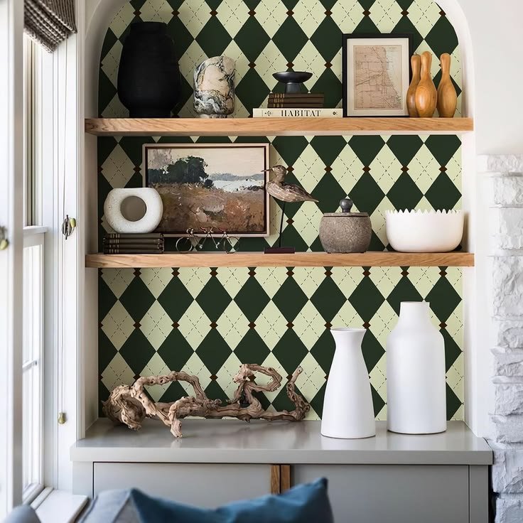 Checkered wallpaper behind rustic wood shelves with ceramic vases, books, and woven baskets