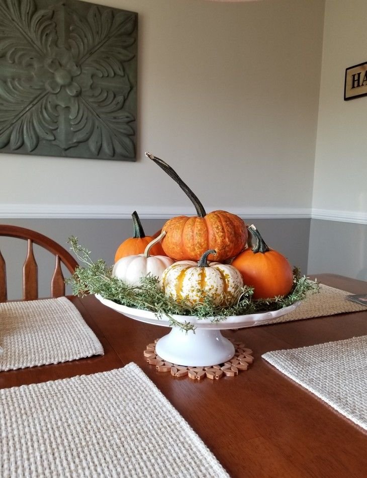 Mini pumpkins arranged with greenery on a wooden tray as a Thanksgiving centerpiece