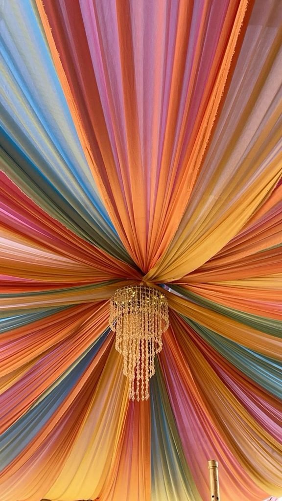 Cobalt-blue fabric ceiling canopy paired with terracotta accents and natural wood in a colorful bedroom.