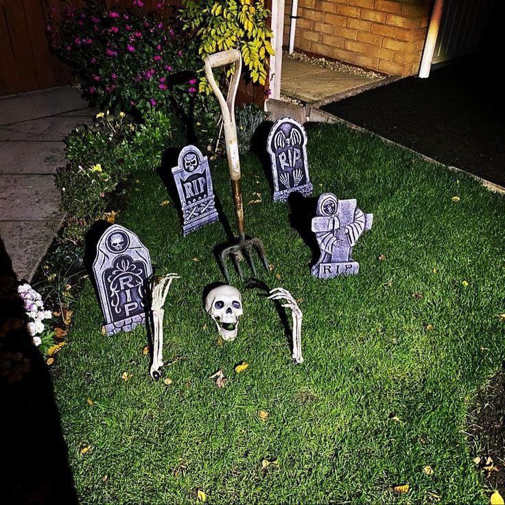DIY Halloween graveyard decorations with tombstones on a front lawn.