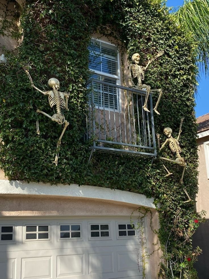 Plastic skeletons climbing the exterior wall of a house for Halloween.