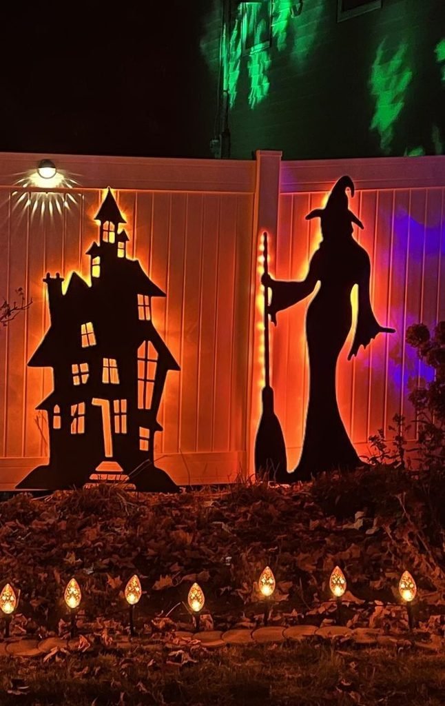 wotch silhouettes decorating a wooden fence for Halloween.