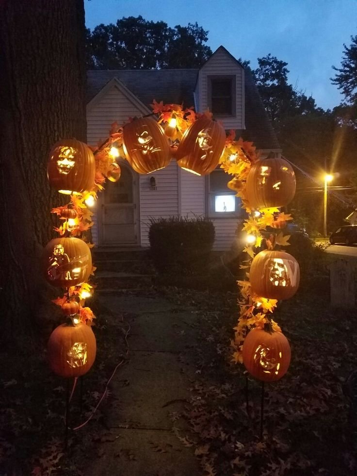 Haunted Halloween garden entrance with twisted branches, pumpkins, and lanterns.