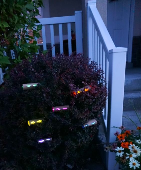 Subtle glowing eyes hidden among bushes in an outdoor Halloween display.